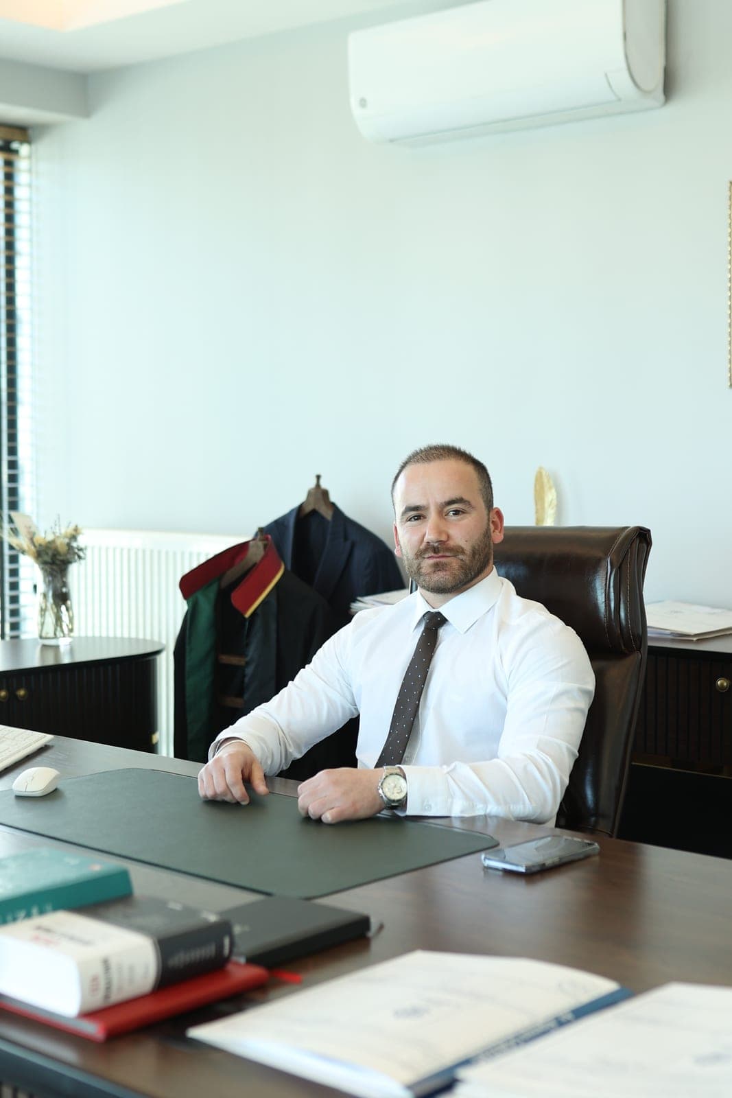 Av. Alperen Gökdağ büroda çalışma masasında, arkada cübbesi